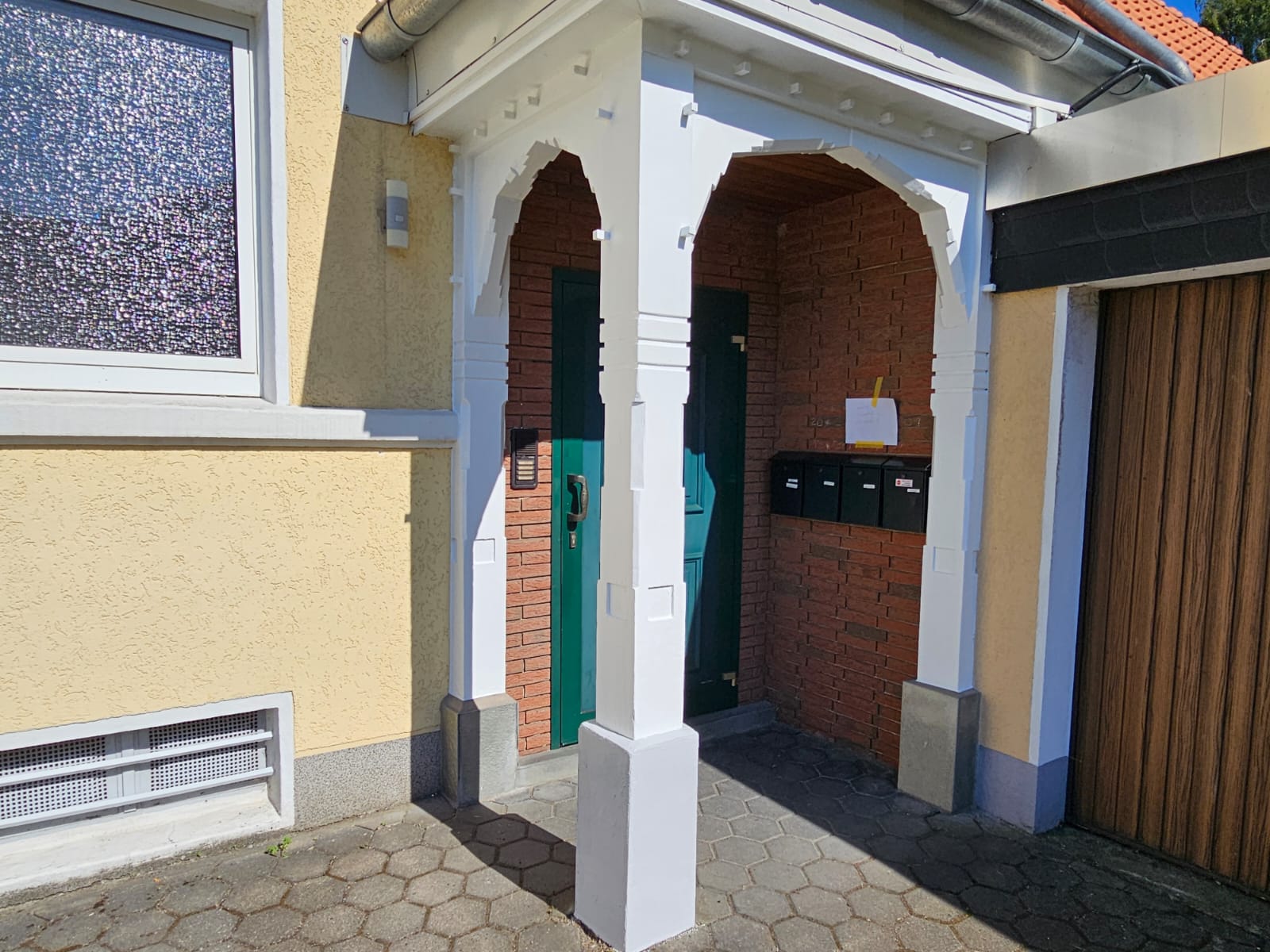 Hauseingang nach der Aufarbeitung mit weiß beschichtetem Holzvorbau