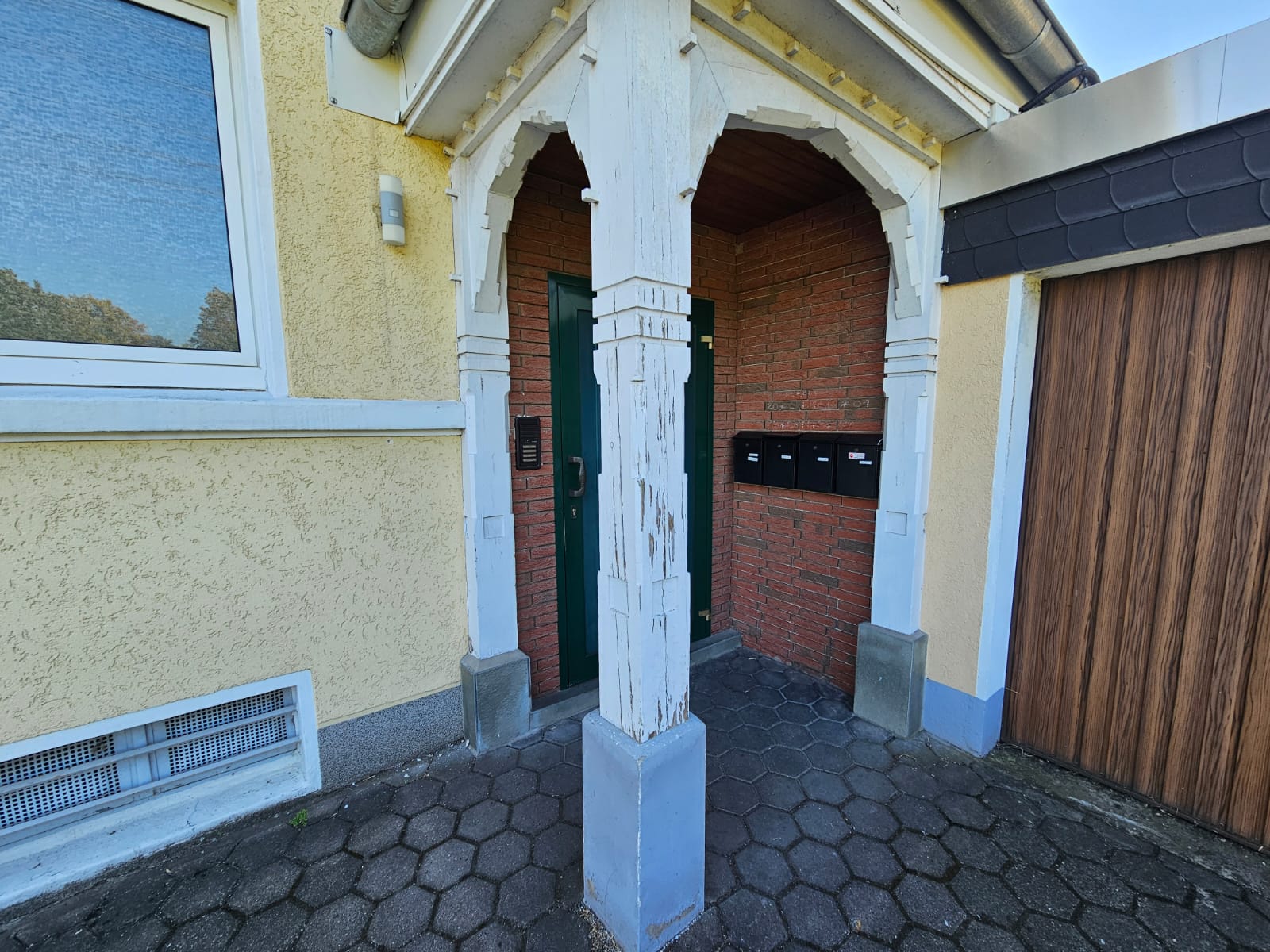 Hauseingang vor der Aufarbeitung mit verwittertem und rissigem Holzvorbau